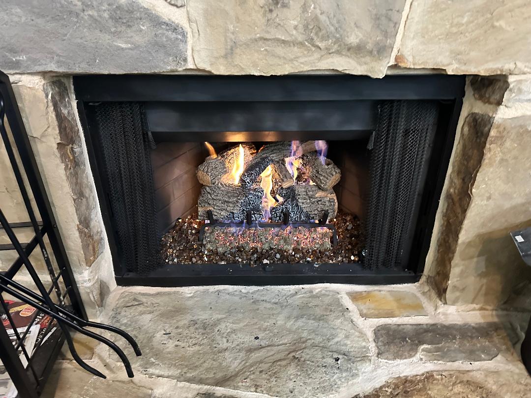 Burning gas log set inside a stone fireplace