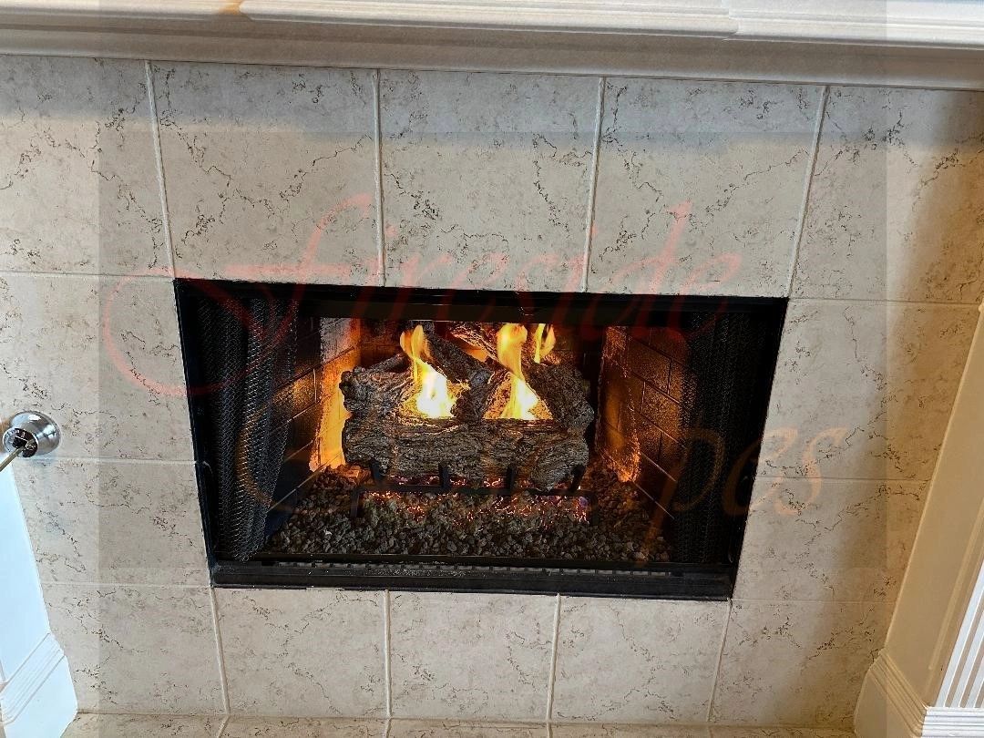 Gas log fireplace in a light stone surround from the Fireside Escapes project gallery