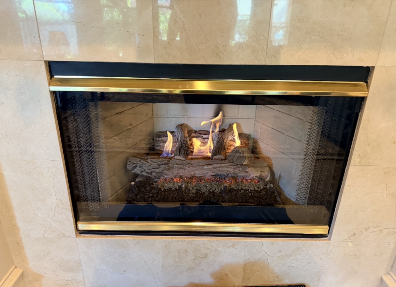 Gas fireplace with burning logs and a marble surround